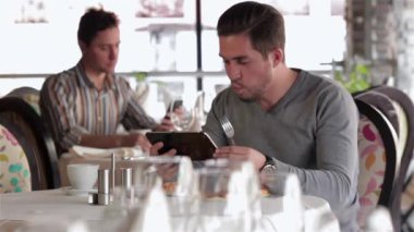 Restoranda, kafede, kafede iş yemeği. Resmi olarak giyinmiş bir adam öğle yemeğinde iç mekanda oturur. Bir adam saati kontrol eder..