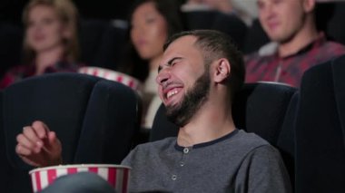 Asyalı erkek bir komedi sırasında duygularını geri tutmaz. Sinema, eğlence ve insan kavramı - mutlu arkadaşlar tiyatroda film izlerken. Çift ve diğer insanlar patlamış mısır yeme ve soda içme