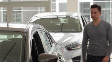 Bir adam iç araç olup olmadığını denetler. Otomatik iş, araba Satılık, teknoloji ve insan kavramı - auto göstermek ya da salon araba satıcısı ile mutlu erkek. Bir satıcı motor gösterisi ile genç adam.