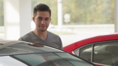 Arabanın alıcı başparmak ortaya çıktı. Otomatik iş, araba Satılık, teknoloji ve insan kavramı - auto göstermek ya da salon araba satıcısı ile mutlu erkek. Bir satıcı motor gösterisi ile genç adam.