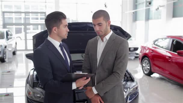 Titta Däcken Ung Bilförsäljare Visar Fördelarna Med Bilen För Kunden — Stockvideo