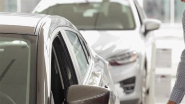 Aracın iç içine bakan bir adam. Yan görünümü. Otomatik iş, araba Satılık, teknoloji ve insan kavramı - auto göstermek ya da salon araba satıcısı ile mutlu erkek. Bir satıcı bir motor ile genç adam