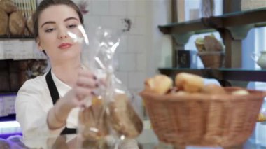 Satıcı taze rulo lar bırakır. Kahve dükkanı veya fırın içinde genç gülümseyen fırıncı taze ekmek, hamur işleri, kekler, makaron, kekler sunmaktadır. Yeni fırın, kahvehane ürün yelpazesine her zaman bir