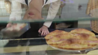 Sevimli kız satıcı macaroon sunuyor. Kahve dükkanı veya fırın içinde genç gülümseyen fırıncı taze ekmek, hamur işleri, kekler, makaron, kekler sunmaktadır. Yeni fırın, kahvehane nin ürün yelpazesine olduğunu