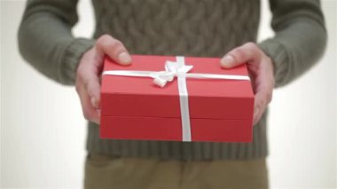 Erkek verir kadar bir hediye kapatın. Noel Baba şapkası, rahat kazak, genç çekici çift gülümseyen, diğer her bir Happy New Year, mutlu Noeller, mutlu sevgililer günü tebrik, hediyeler, gülüyor sunar