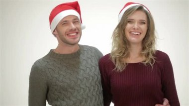 Noel Baba şapkalı mutlu çift kucaklaşırken gülüyor. Santa şapka genç çekici çift, rahat kazak, gülümseyerek, mutlu bir yeni yıl, Mutlu Noeller, Happy Valentine birbirlerini tebrik