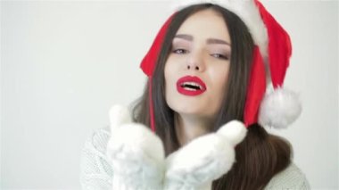 Noel şapkalı güzel bir kadın öpücük yolluyor. Beyaz arka planda gülümseyen mutlu kız. Güzel kadın, kız, Noel şapkalı kadın stüdyoda poz veriyor. Noel hediyeleri. Sıcaklık kavramı
