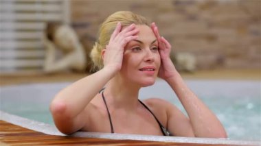 Suda dinlenen genç bir kadın. Mutlu kadın jakuzide dinleniyor. Kaplıca salonundaki kadın..