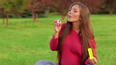 Hamile bir kadın sabun köpüğü üflüyor. Çocuk bekleyen bir kadın. Hassasiyet, hamilelik ve annelik kavramı. Kadın şehir parkında yürüyor, şefkatle dolup taşıyor.