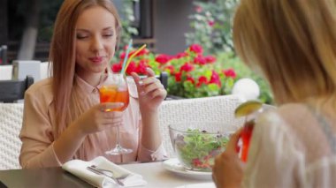 Şirin kız konuşuyor. Kadınların rahat kafe terasında sevinir Toplantı