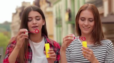 Kabarcık açık mutlu yaşam tarzı üfleme güzel ve genç birbayan. Güzel genç kız şehir sokak sabun köpüğü üfleme