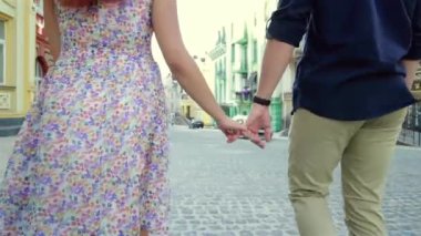 Çift el ele şehirde geziniyor. Genç kadın ve şehir parkında el ele yürüyen adam