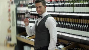 Şarap test. Kendine güvenen erkek sommelier şarap raf yakınındaki dururken şarap ile test