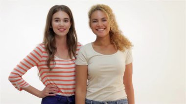 Başarılı kadın baş parmağını kaldırıyor. Heyecanlı, beyaz arka planda izole güzel bir kadın. Birlikte duran iki genç kız arkadaş. Kahverengi saçlı, beyaz ve kızıl saçlı kız kameraya gülümsüyor..