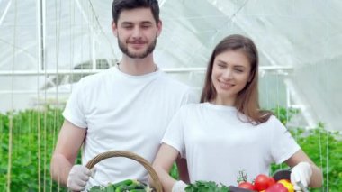 Doğrudan kameraya gülümseyen hasat sonra erkek ve kadın çiftçiler. Genç Ziraat hasat izlemek. Genç çiftçilerin yetişir ve organik sebze hasat