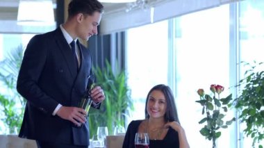 Restoranda düğün yıldönümü kutlamaları. Restoranda romantik bir akşam yemeği. Seven adam elinde bir şişe şarap ve bir bardağa seyir ederken restoran ziyaret çift genç