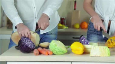 Sebze Dilimleme kapatın. Genç gülümseyen arkadaşlar kesilmiş sebzeler ise mutfakta yemek. Birlikte yemek yiyecek.