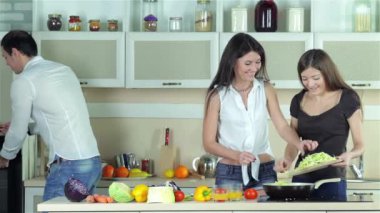 Üç arkadaş bir piknik için salata hazırlayın. Genç gülümseyen arkadaşlar kesilmiş sebzeler ise mutfakta yemek. Birlikte yemek yiyecek.