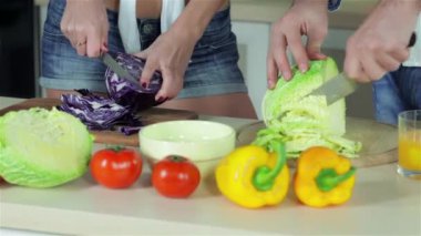 Arkadaşlar birlikte lahanaları dilimlenmiş. Genç gülümseyen arkadaşlar kesilmiş sebzeler ise mutfakta yemek. Birlikte yemek yiyecek.