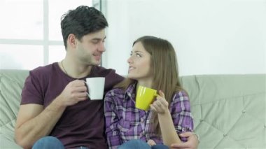 Çift, elinde fincanlarla kanepede otururken birbirine bakıyor. Mutlu arkadaşlar birlikte eğlenir. Neşeli gençler kanepede oturup çay ya da kahve içerken birbirlerine sarılıp eğleniyorlar.