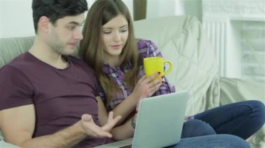 Mutlu Arkadaşlar birlikte eğlenirler. Neşeli gençler kanepede oturup çay içiyorlar. İnsanlar gülümsemeye ve gülmeye devam ediyor..