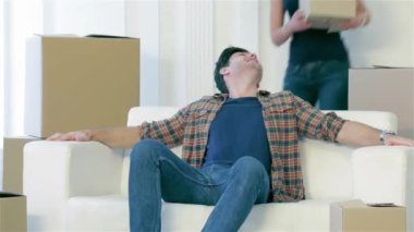 Yeni eğlenceli bir hayat. Süre çift aşk hareketli ve tutmak ellerini ve kameraya bakarak kutusunda kutuları arasında boş bir daire içinde kanepede oturan aşık genç ve güzel bir çift