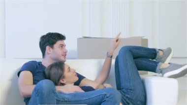 Ev ve yeni bir hayata tamiri hareket. Çift kanepe erkek ve kadın birlikte boş bir dairede sarılma sırasında taşıma kutuları arasında yatan aşık