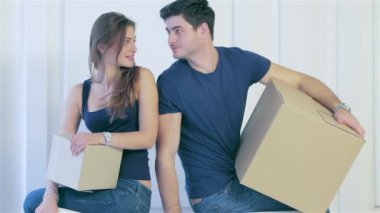 Hareketli, onarır, yeni daire. İki kız ve adam hareketli kutular elinde tutup, erkek ve kadın kanepede kasa içi boş bir daire arasında arkasında ayakta iken kameraya bakıyor