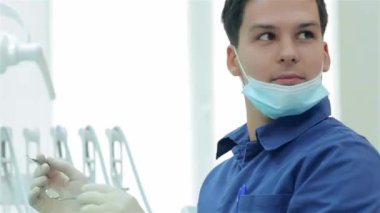 Diş hekimi diş hekimliği önce. Diş hekimi diş bir enstrüman Yardımcısı bakıp gülümseyerek elinde tutan