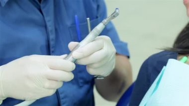 Genç başarılı dişçi resepsiyonda gurl. Sadece matkap diş ve diş sandalyede oturan bir kız ile bir diş gülümseme portresini tutan nedir bir dişçi closeup