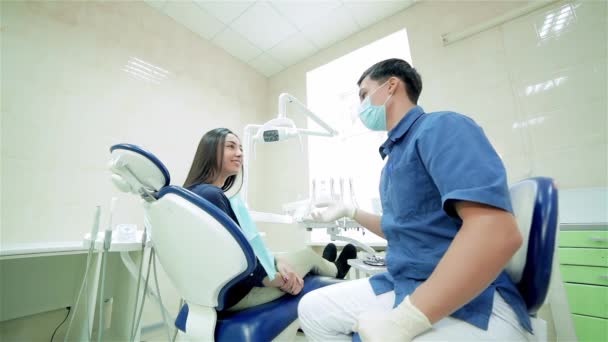 年轻的成功牙医的磋商 掩码中的牙医说给病人 然后他们一起旋转 并显示一个拇指端起相机 — 图库视频影像