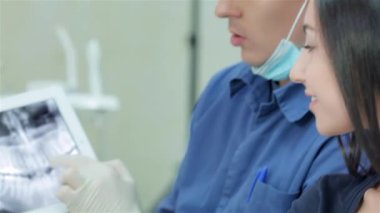 Bir resepsiyonda diş hekimi. Bir diş hekimi ve bir kız portresi. Dişçi dişlerini bir x-ışını fotoğrafı bir close-up tablet üzerinde gösterir.