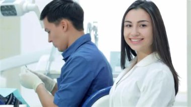 Yeni çalışma günü diş hekimleri. Diş hekimi diş ve asistan kız dişler gülümseme ve başparmak yukarıya ele alır