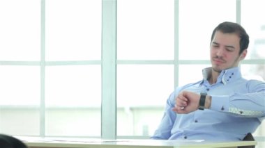 İşe geç kaldım. İşadamı saatine dikkat çekerken, iki başarılı iş adamı resmi olarak iş ofisinde karşılıklı oturuyorlar ve bir dizüstü bilgisayarda çalışıyorlar..