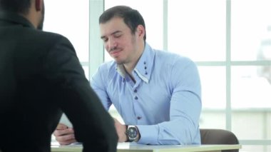 Sözleşme gözden geçirdim. İşadamı belgeleri formal giyim ve iş yerinde bir dizüstü bilgisayar bir iş ofiste masada oturan iki başarılı bir işadamı iken bakarak.