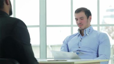 Bir iş planı hazırlanıyor. Müzakere masasına ofis ve iş bir dizüstü bilgisayar ve ekrana bakarak otururken iki başarılı bir iş adamı. İş adamları formal giyim giyinmiş