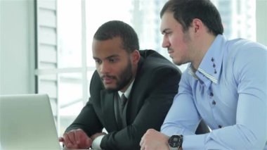 Ofiste iki iş adamları. Çalışan bir iş ofiste formal giyim ve iş yerinde bir dizüstü bilgisayar birbirine yanındaki masada oturan iki başarılı bir işadamı iken başarılı genç insanlar
