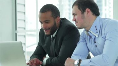 Güzel iş. Parmağını masasında ofiste formal giyim göstermek yukarıya bir gülümseme ile iki emin işadamı.