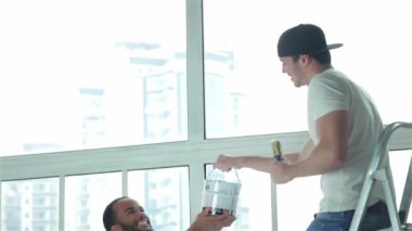 Resim, yer değiştirme ve onarım daire. İki işçi yeni bir dairede onarımları yapmak. Bir adam başka bir adamla merdivenin boya alır