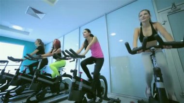 Fitness bisiklet birlikte. Spor salonunda sabit bir bisiklet üzerinde dört arkadaş pedal