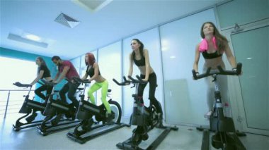 Spor salonunda grup egzersizleri. Beş pedal arkadaşları ve görünüşüne önünde bir sabit Bisiklet spor salonunda spor. Sporcular spor kıyafetler giymiş.