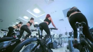 Kızlar kadın sporcular üzerinde sabit bir bisiklet grubu. Güzel spor.