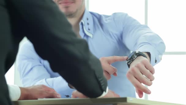 時間の仕事 交渉に座って真面目なサラリーマンはオフィスのテーブルし あなたの時計を示します ビジネスの人々 はフォーマルな服装に身を包んだ — ストック動画