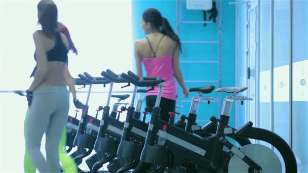 在健身房健身锻炼 四位年轻的女士坐上和在模拟器上脚踏 — 图库视频影像