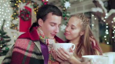 Noel mobilyalı bir odada hediyeler tutan kazak ve eşarp giymiş sevgi dolu bir çift. Aşık adam genç çift ve evde kazak ve eşarp giyen güzel kız.