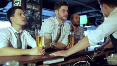 Dört arkadaş işadamları bira içmek ve sevinmek ve birlikte barda Tv izlerken bağırmak. Başarılı işadamları arkadaşlar tv'de futbol izlerken bir bira ile barda birlikte eğleniyor.