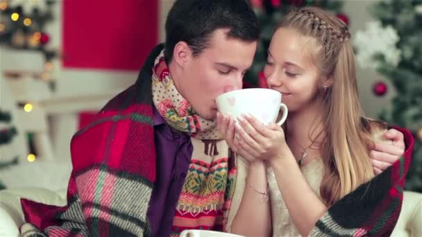 在圣诞家具房里 穿着毛衣和围巾的情侣们拿着礼物 年轻夫妇在爱的男人和漂亮的女孩穿着毛衣和围巾在家里 — 图库视频影像