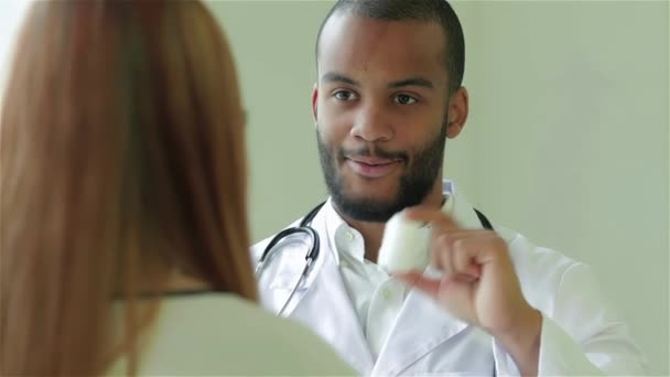 注意深い医者は患者に耳を傾け 最高の医院で診断する 笑顔の医師は患者の話を聞き 病院で薬の処方箋を書きます 礼儀正しい医者 — ストック動画