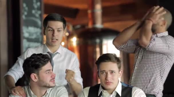 四个朋友商人喝着啤酒 在酒吧里一起看电视 欢欣鼓舞 一起大喊大叫 成功的商人朋友在酒吧里玩得很开心 在电视上喝啤酒看足球 — 图库视频影像