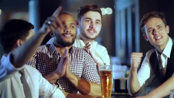 4人の友人ビジネスマンがビールを飲み バーでテレビを見ながら一緒に喜び テレビでサッカーを見てビールと一緒にバーで一緒に楽しんで成功したビジネスマンの友人 — ストック動画